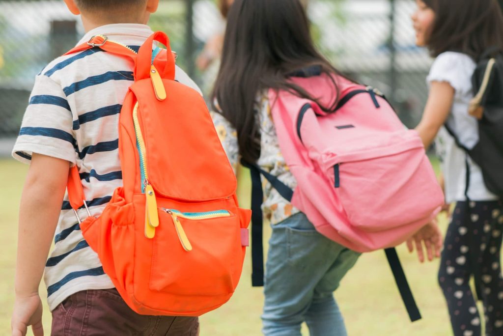 Trois élèves de l'école primaire vont main main garçon fille avec des sacs d'école retour début des cours d'école chaude journée d'automne retour à l'école peu d'élèves de première année